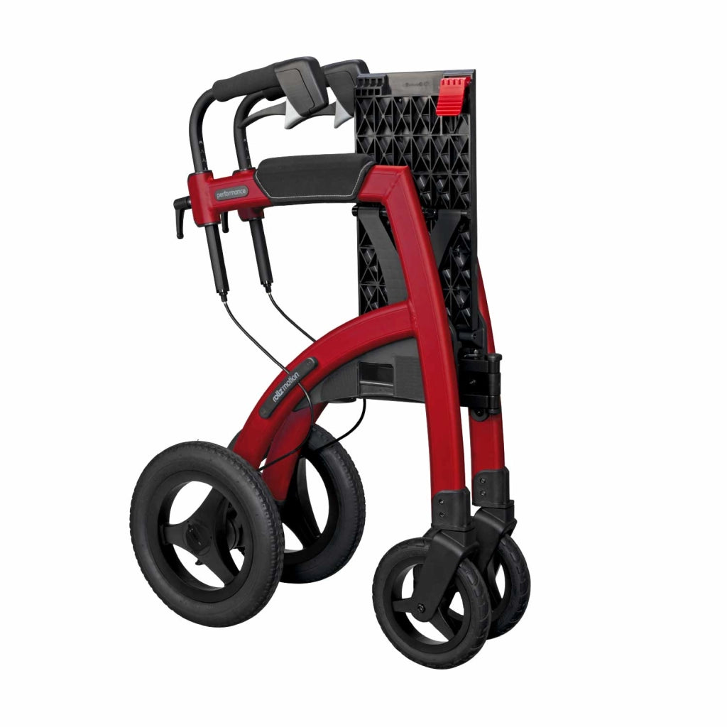 Rollz Motion Performance in Ruby Red in zusammengefalteter Position, platzsparend stehend mit gut sichtbaren ergonomischen Griffen und Hinterrädern.
