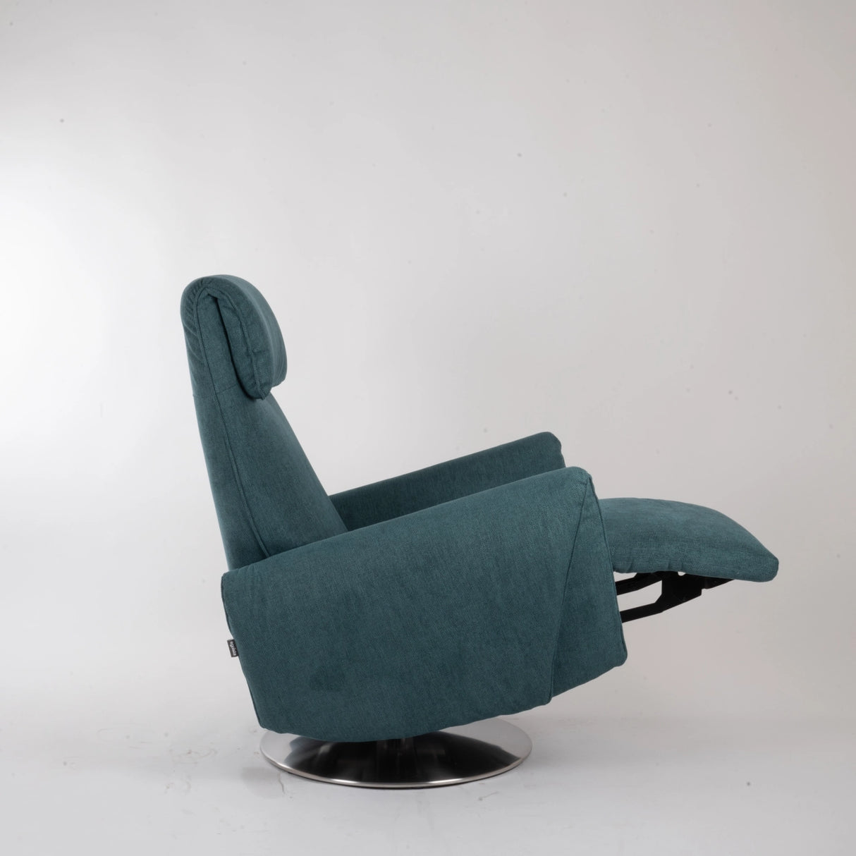 Dreh-Relaxsessel Muna von egoista in petrolfarbenem Stoffbezug, seitlich aufgenommen in Liegeposition mit ausgefahrener Fußstütze, ergonomischer Rückenlehne und drehbarem Metallfuß – ideal für höchsten Sitzkomfort und Entspannung.