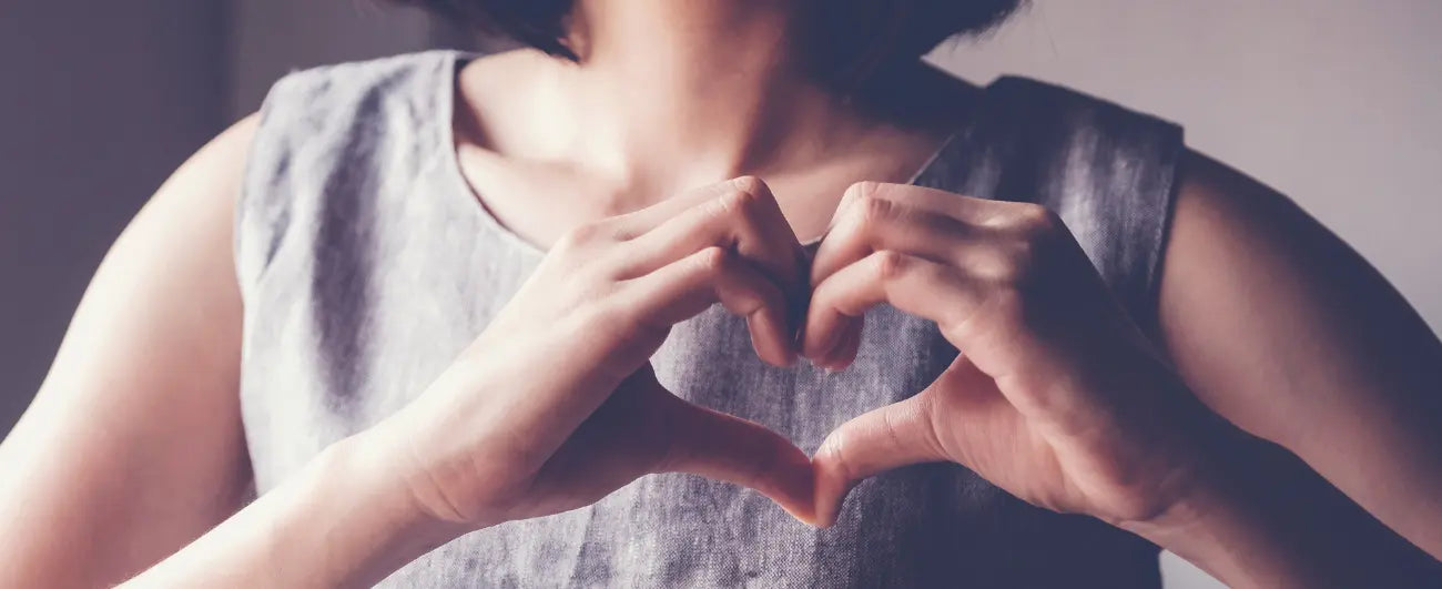 Frau formt ein Herz mit den Händen vor ihrem Herzen.